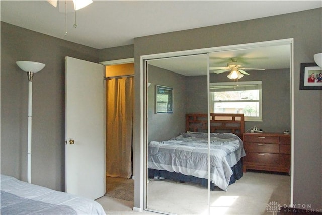 bedroom featuring light colored carpet, a closet, and a ceiling fan