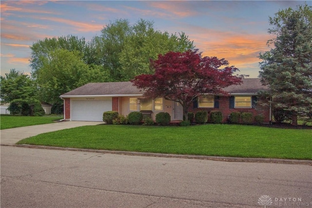 view of front of house with concrete driveway, an attached garage, brick siding, and a front lawn