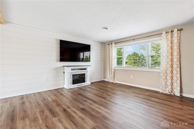 7217 State Route 380, Chester Twp, OH 45177 - unfurnished living room featuring wood finished floors, baseboards, a fireplace, and wooden walls