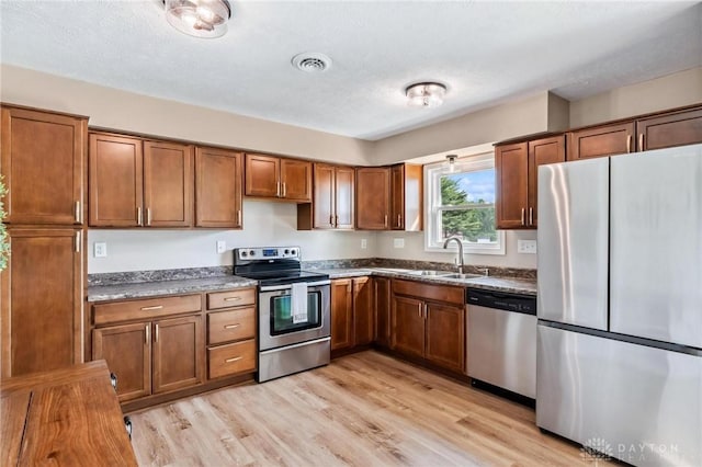 7217 State Route 380, Chester Twp, OH 45177 - kitchen with stainless steel appliances, a sink, brown cabinetry, light wood finished floors, and a textured ceiling