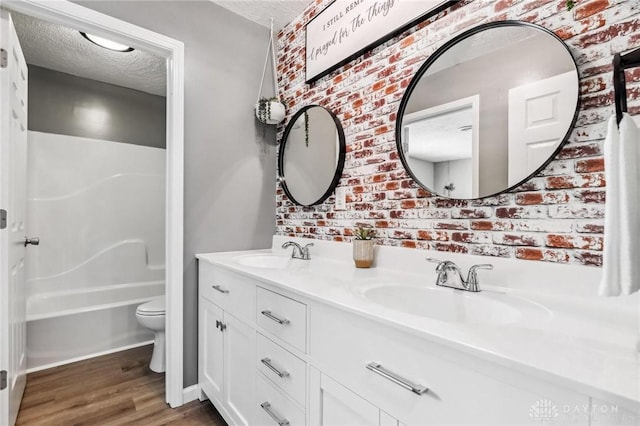 7217 State Route 380, Chester Twp, OH 45177 - full bathroom with a textured ceiling, wood finished floors, toilet, and double vanity