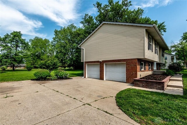 6399 Kimberly Dr, Fairfield Twp, OH 45011 - view of home's exterior with a garage, concrete driveway, a lawn, and brick siding
