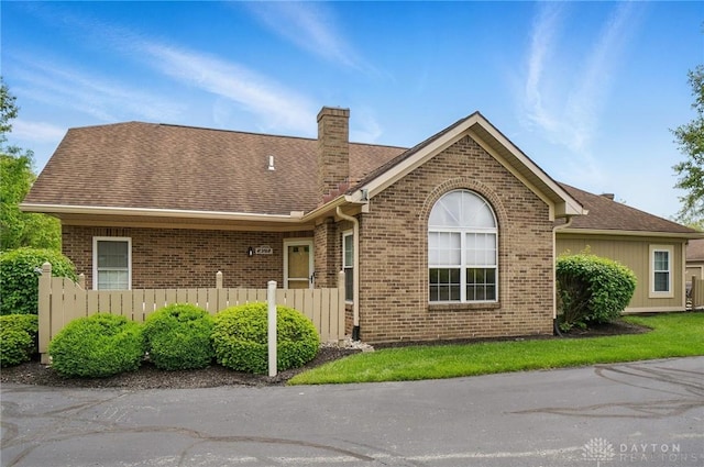 single story home featuring brick siding, a chimney, and fence