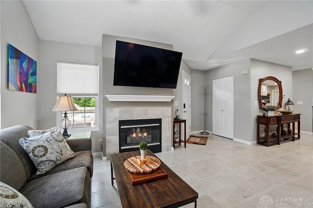 living room featuring a fireplace, vaulted ceiling, and baseboards