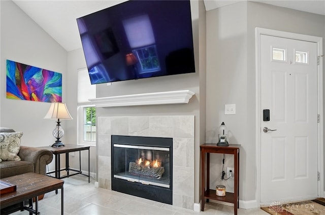 living area featuring a fireplace, lofted ceiling, and baseboards