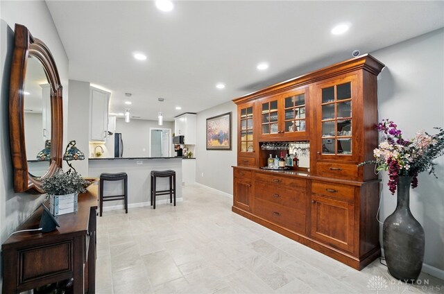 bar area with refrigerator, recessed lighting, hanging light fixtures, black microwave, and baseboards