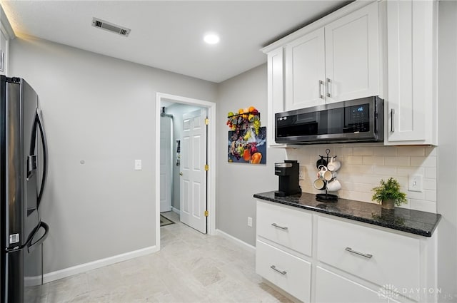 kitchen with stainless steel microwave, black fridge, tasteful backsplash, dark stone countertops, and baseboards