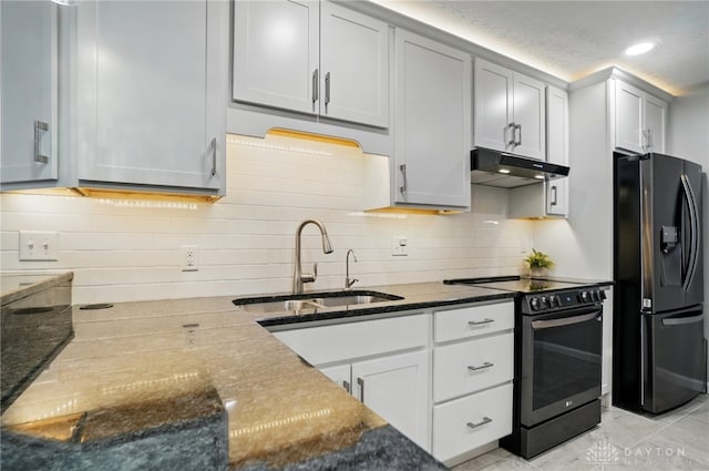 kitchen with black appliances, a sink, under cabinet range hood, dark stone counters, and backsplash