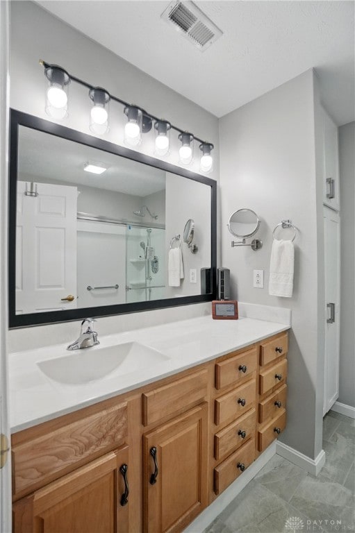 bathroom featuring vanity, marble look tile flooring, an enclosed shower, and baseboards