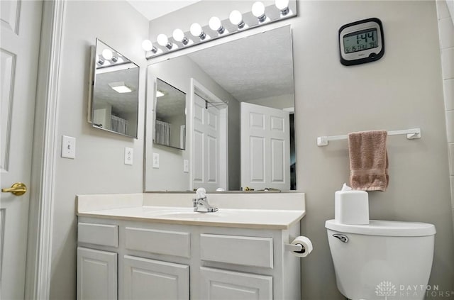 bathroom with toilet, vanity, and a textured ceiling
