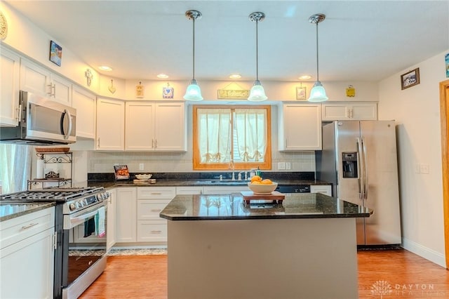 849 Wind Blf, Springboro, OH 45066 - kitchen with appliances with stainless steel finishes, light wood-type flooring, decorative backsplash, a sink, and a kitchen island