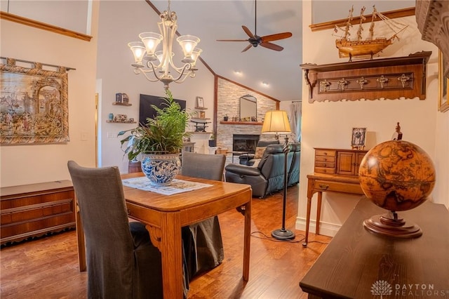849 Wind Blf, Springboro, OH 45066 - dining space featuring a ceiling fan, light wood finished floors, vaulted ceiling, a large fireplace, and a chandelier