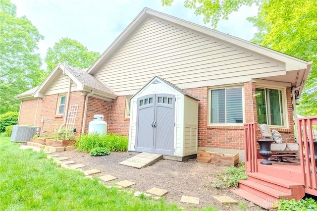 849 Wind Blf, Springboro, OH 45066 - rear view of house featuring a storage shed, brick siding, a wooden deck, central AC, and an outdoor structure