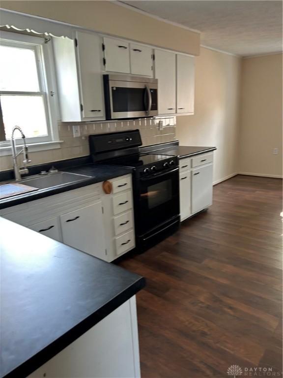 20 N 10th St, Miamisburg, OH 45342 - kitchen with stainless steel microwave, black range with electric cooktop, dark countertops, and crown molding