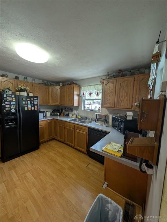 7430 S Kessler Fred Rd, West Milton, OH 45383 - kitchen featuring black appliances, brown cabinetry, light countertops, light wood-type flooring, and a textured ceiling
