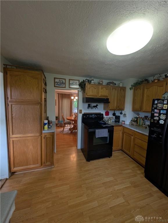 7430 S Kessler Fred Rd, West Milton, OH 45383 - kitchen featuring black appliances, a textured ceiling, light wood-style flooring, light countertops, and under cabinet range hood