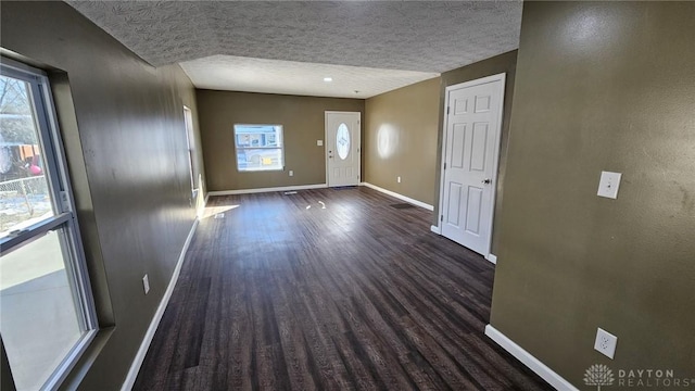 foyer entrance featuring dark wood-style flooring, baseboards, and a textured ceiling