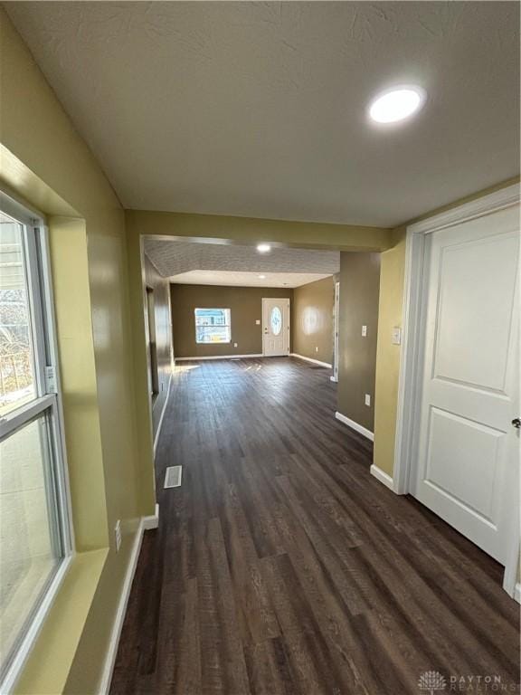 unfurnished living room with baseboards and dark wood-style flooring