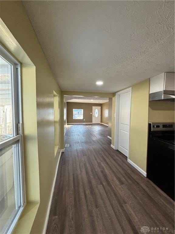 hallway featuring dark wood finished floors, baseboards, and a textured ceiling