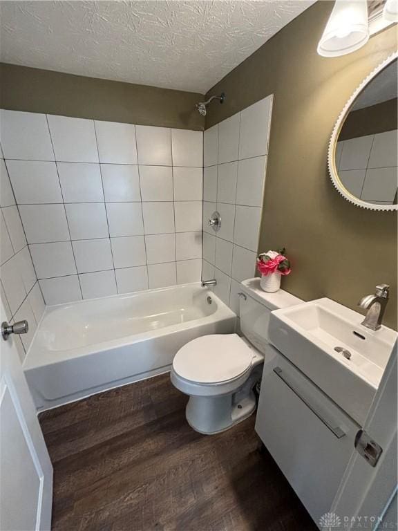 bathroom with wood finished floors, a textured ceiling, shower / bath combination, toilet, and vanity