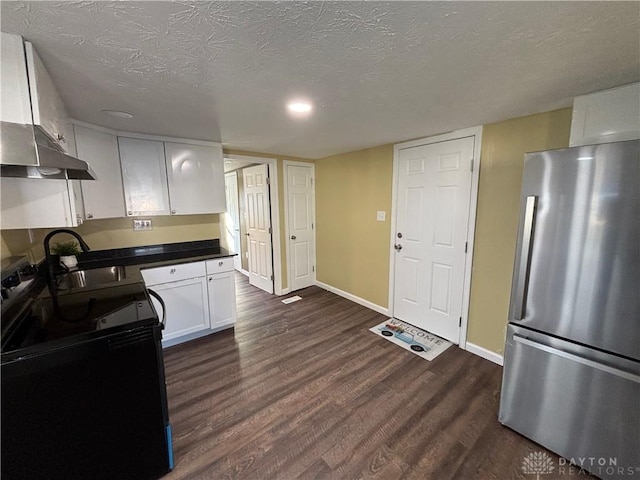 kitchen with freestanding refrigerator, a sink, black range with electric cooktop, wall chimney range hood, and dark wood-type flooring