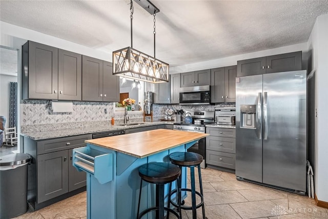 1493 N Sulphur Springs Rd, West Alexandria, OH 45381 - kitchen with stainless steel appliances, butcher block countertops, a kitchen bar, decorative backsplash, and a textured ceiling