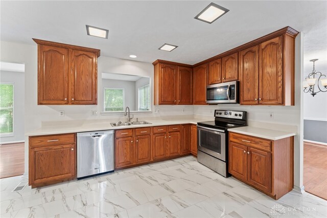 kitchen with appliances with stainless steel finishes, a sink, light marble finish floors, brown cabinetry, and recessed lighting