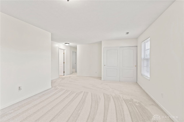 unfurnished room with light carpet and baseboards