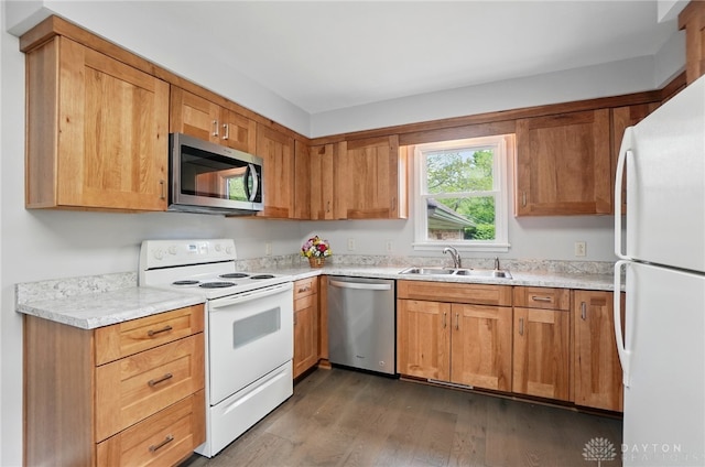 kitchen featuring stainless steel appliances, a sink, dark wood finished floors, and light countertops
