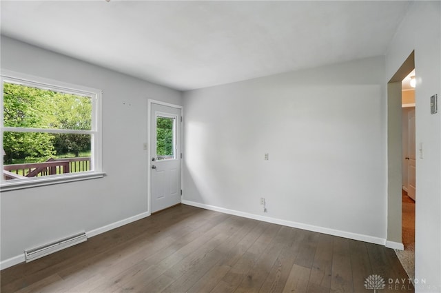 spare room featuring baseboards and dark wood-type flooring
