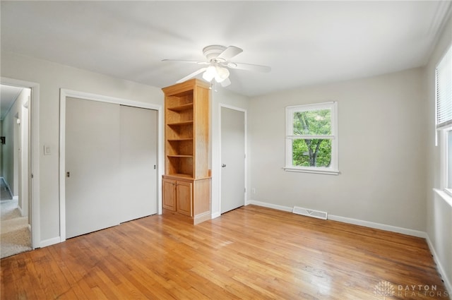 unfurnished bedroom with light wood-style floors, a closet, baseboards, and a ceiling fan