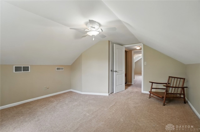 additional living space featuring light colored carpet, vaulted ceiling, a ceiling fan, and baseboards