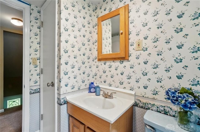 bathroom with wallpapered walls, toilet, and vanity