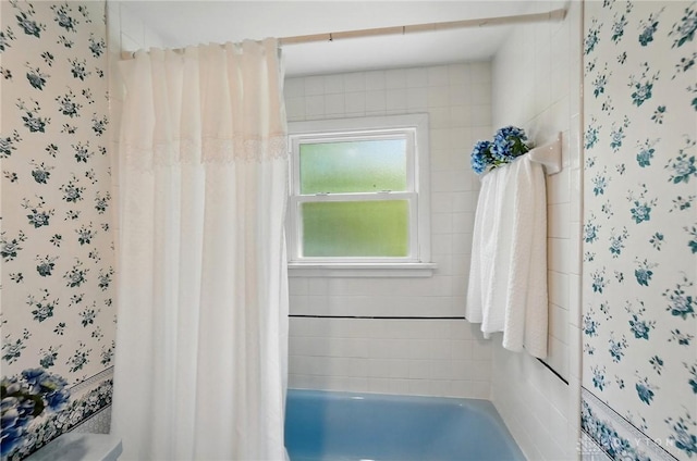 bathroom featuring wallpapered walls, a bath, and curtained shower