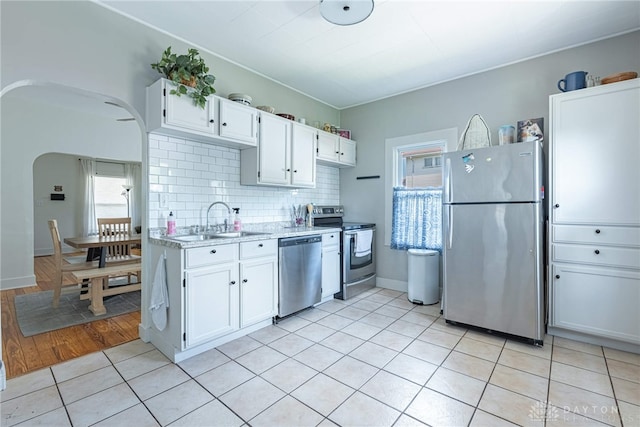 2526 Saint Charles Ave, Dayton, OH 45410 - kitchen with stainless steel appliances, light countertops, arched walkways, white cabinetry, and backsplash