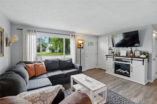living area with wood finished floors, a textured ceiling, and baseboards