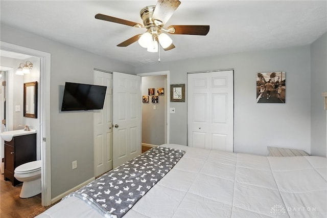 bedroom with two closets, wood finished floors, ceiling fan, and baseboards