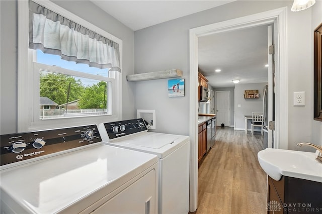 clothes washing area featuring separate washer and dryer, light wood-style flooring, and baseboards