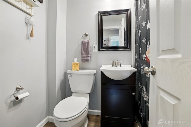 bathroom with baseboards, wood finished floors, toilet, and vanity
