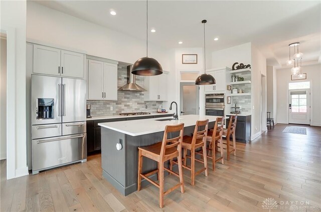 1264 Normandy, Clearcreek Twp, OH 45458 - kitchen featuring stainless steel appliances, open shelves, wall chimney exhaust hood, decorative backsplash, and light wood-style flooring