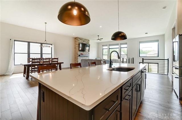1264 Normandy, Clearcreek Twp, OH 45458 - kitchen featuring a sink, hardwood / wood-style floors, pendant lighting, a kitchen island with sink, and light stone counters