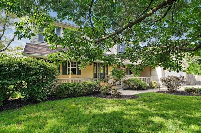view of property hidden behind natural elements with a front lawn and covered porch