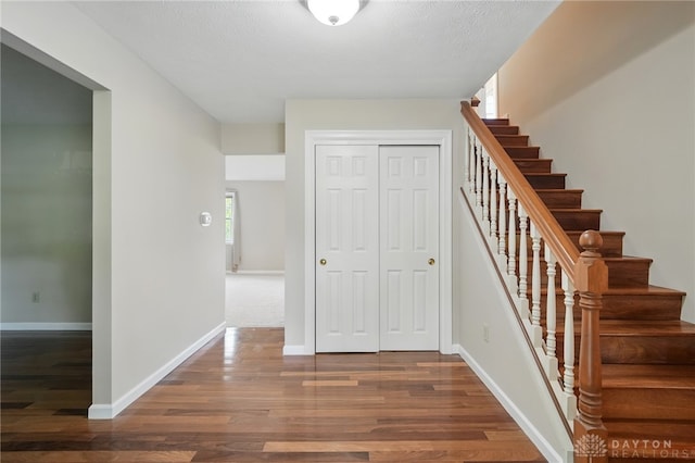 staircase featuring wood finished floors and baseboards