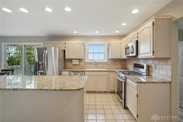 2337 Eastwind Dr, Beavercreek, OH 45434 - kitchen with stainless steel appliances, a sink, light tile patterned floors, tasteful backsplash, and light stone counters