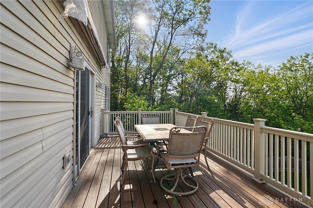 deck with outdoor dining space and view of scattered trees