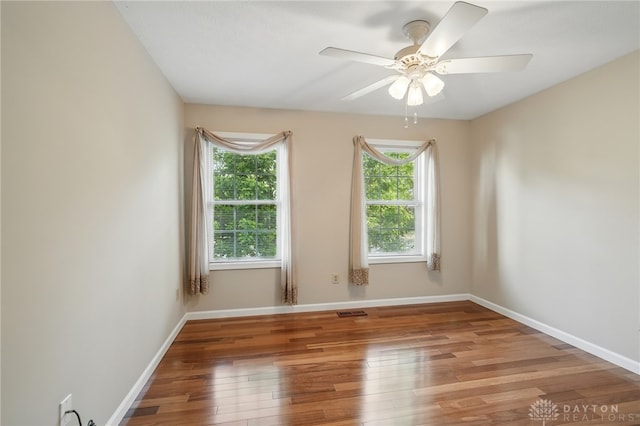 unfurnished room with wood finished floors, a ceiling fan, and baseboards