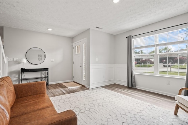 unfurnished living room with wood finished floors, a textured ceiling, and recessed lighting