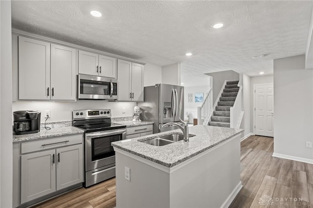 kitchen featuring stainless steel appliances, a sink, gray cabinetry, light wood finished floors, and recessed lighting