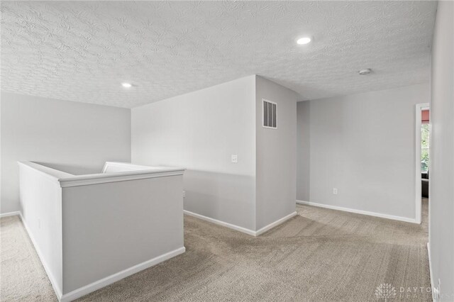 hallway with carpet floors, a textured ceiling, baseboards, and recessed lighting