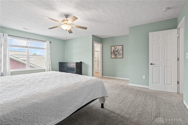 carpeted bedroom with baseboards, a textured ceiling, a ceiling fan, and connected bathroom
